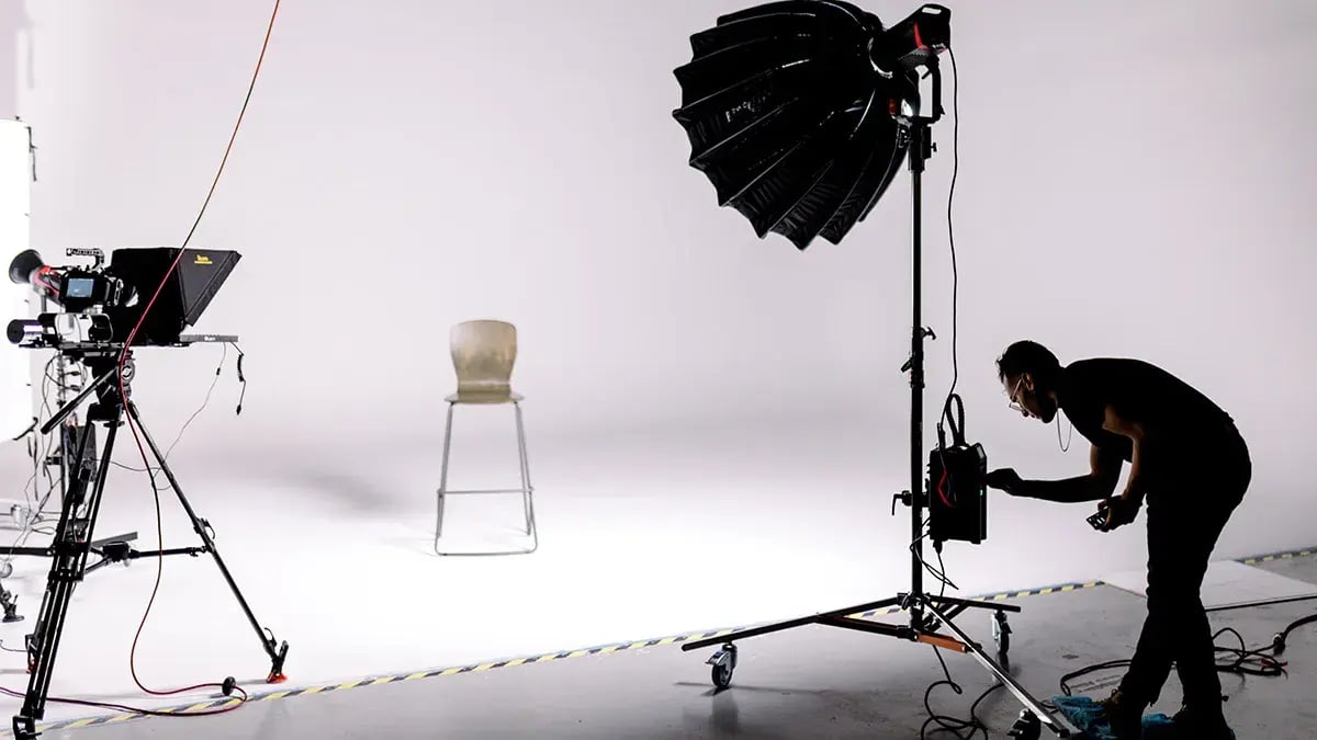 A video production crew member lights a video studio using high end film equipment.