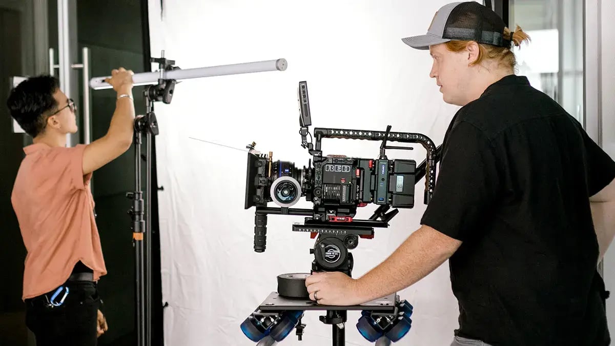 two filmmakers set up a camera and lighting during a video production for a business