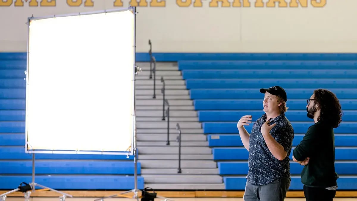 two Charter & Co team members stand inside of a non-for-profit private school discussing a fundraising video project