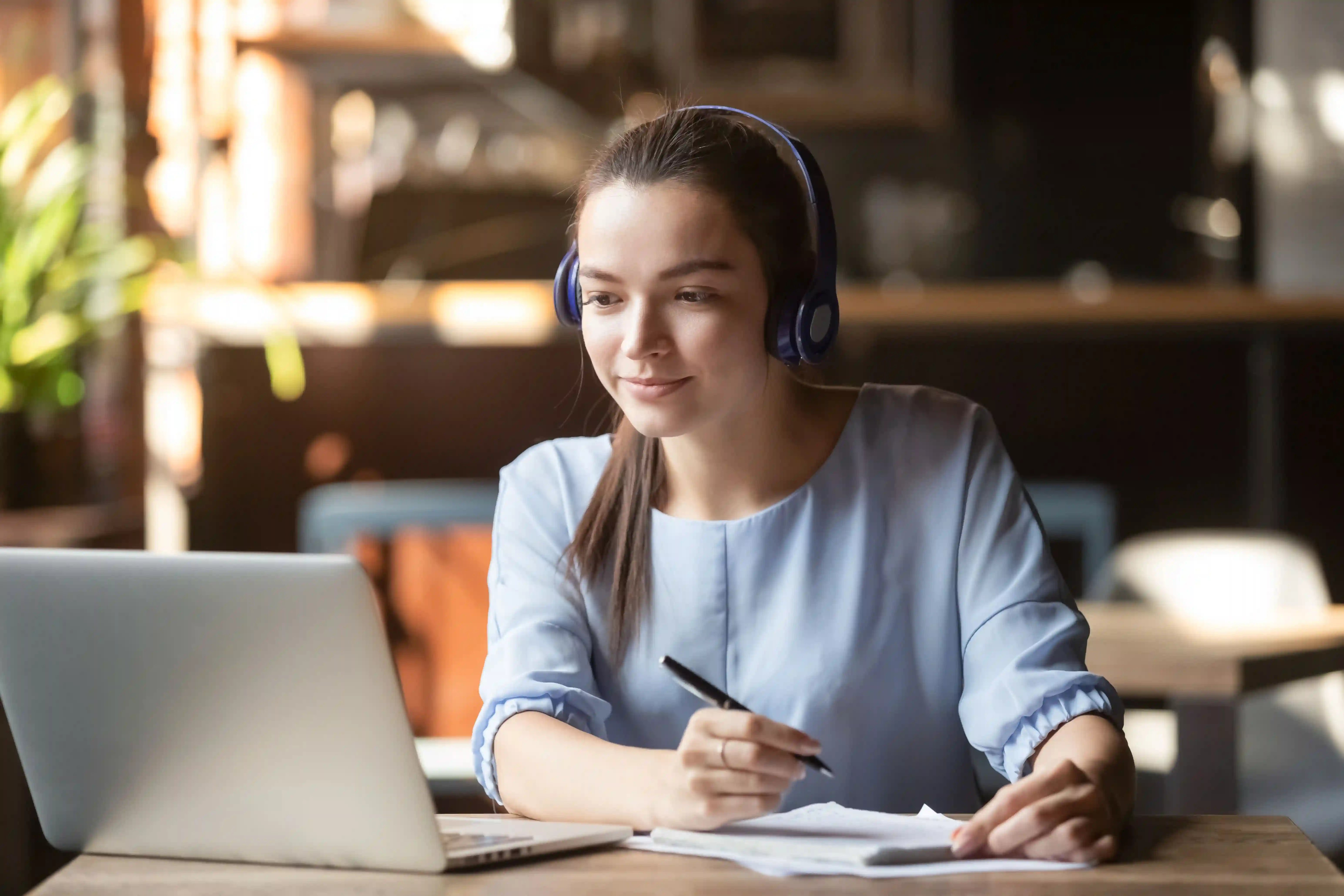 a woman watches an educational video and takes notes